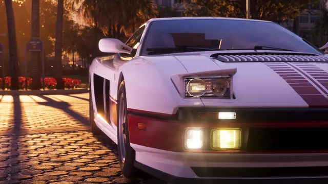 Front three-quarter on a cobbled street at sunset. Twin round lamps sit inside each rectangular housing, with a yellow fog lamp lit below, and the bonnet carries a red gradient stripe over slatted vents. The lower body is maroon against white, which is a period-correct Testarossa arrangement rather than a Rockstar invention.