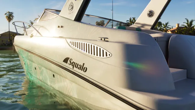 Close on the hull. A shark fin logo sits beside the Squalo name, which fits, squalo is Italian for shark. The arch above carries the Shitzu maker mark. The white gelcoat has a palm frond pattern worked into it that is invisible at distance.