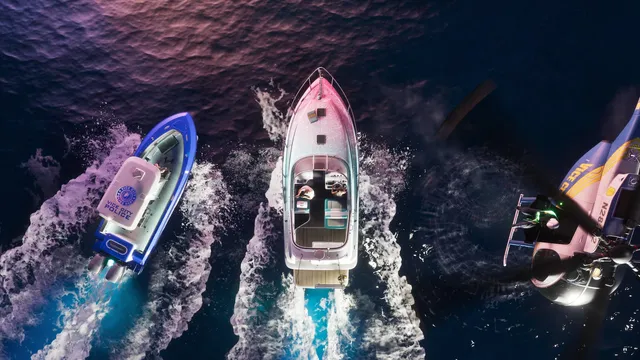 Overhead at night. A Vice City Police boat runs alongside the Squalo while a police helicopter holds station to starboard with its spotlight on the water and rotor wash visible below it. This is the clearest evidence in any official image that the wanted system follows you onto the water, with air support.