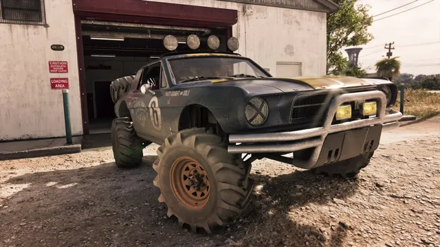 Parked on gravel outside a loading bay. A 1960s fastback coupe lifted onto agricultural tyres and rusted steel wheels, with a four-lamp roof bar, a skid plate and both headlights taped. The door carries Wyman's World, the words parts bought and sold, and race number 6, tying an Ultimate Edition car to the salvage yard listed on our places page.